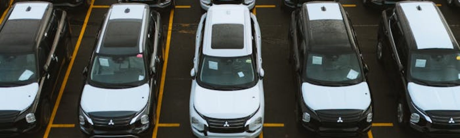 Aerial view of numerous cars in a parking lot, showcasing lined automobiles for sale or storage.